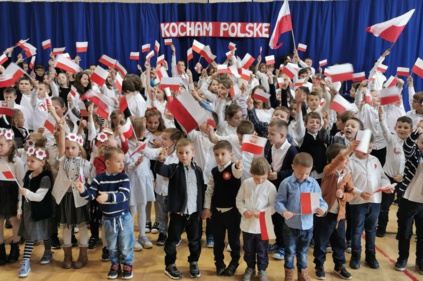 Obchody Narodowego Święta Niepodległości w Szkole Podstawowej w Marcinkowicach - dzieci na sali gimnastycznej wymachują biało-czerwonymi chorągiewkami